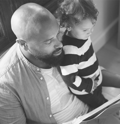 Un homme lit un livre à son enfant. 