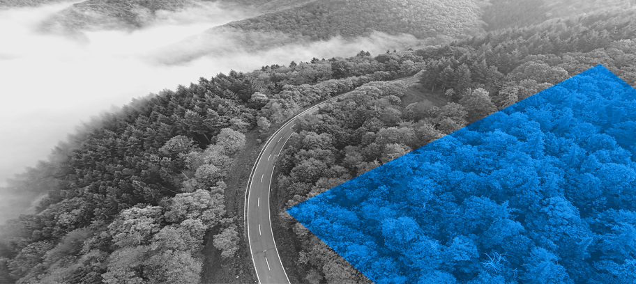 Cheminées industrielles combinées à une vue aérienne d'une route serpentant à travers une forêt. 