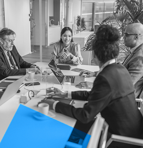 Un groupe d’employés de bureau discute affaires autour d’une table dans une salle de conférence. 