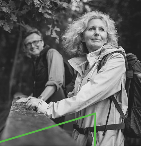 Une femme et un homme habillés en tenue de plein air faisant une randonnée dans les bois